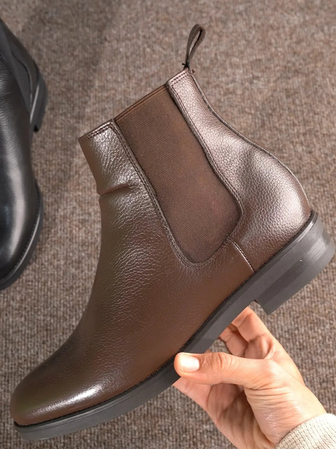Une bottine chelsea en cuir grainé tenue à la main